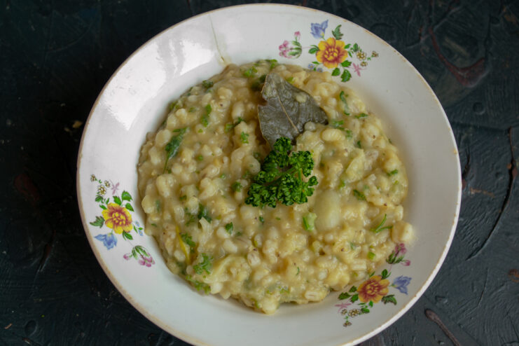Serving the Hot Kulesh Serving portion of vegan kulesh with pearl barley in a patterned bowl