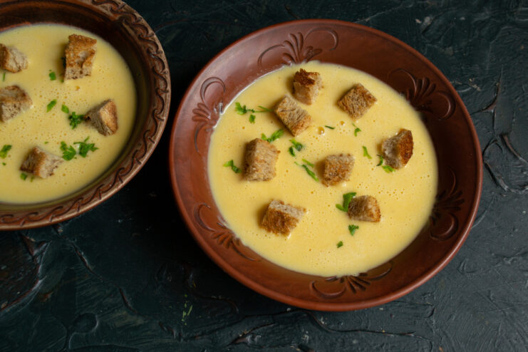 A portion of pumpkin cheese soup sprinkled with fresh herbs and croutons