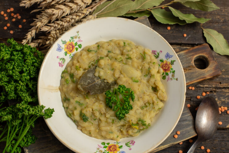 Vegan kulesh with pearl barley and lentils in a bowl with fresh herbs
