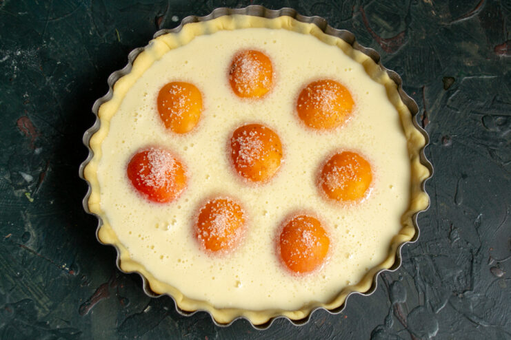 Sugaring the fruit Sprinkling sugar over the apricot halves before baking