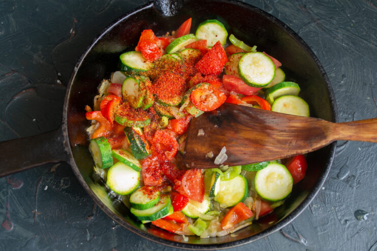 Seasoning the Vegetables Sprinkling sweet paprika and seasonings over the cooking vegetables