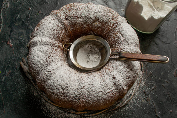 Dusting with powdered sugar Dusting the chocolate cake with powdered sugar through a sieve