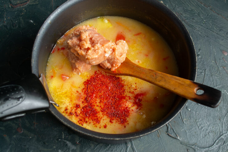 Seasoning with smoked paprika Seasoning the simmering fish soup with red smoked paprika