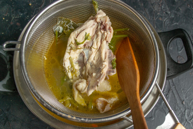 Pouring the chicken broth Straining rich chicken broth through a fine mesh sieve into the soup pot