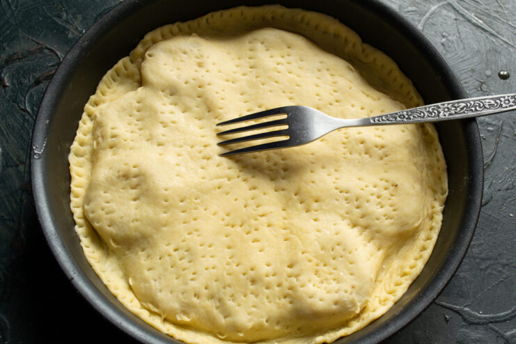 Preparing for Baking Pricking tart dough with a fork directly in the skillet