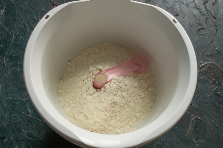 Sifted flour and dry yeast in a white mixing bowl