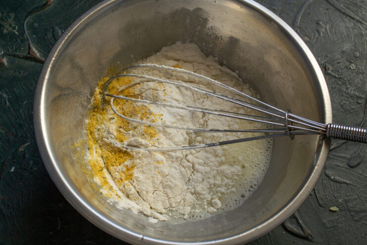 Batter ingredients Adding wheat flour and milk to the whisked egg in a bowl.