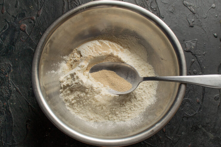 Wheat flour and dry yeast mixed in a metal bowl