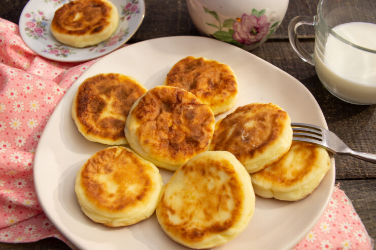 Fluffy homemade farmers cheese pancakes served with sour cream and milk
