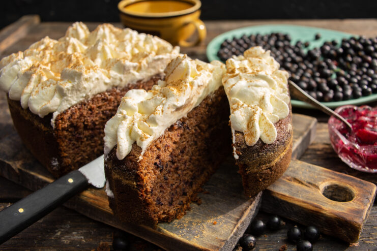 Fluffy dark chocolate and blackcurrant cake topped with whipped cream and ground cinnamon