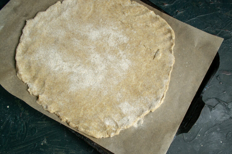 Transferring the Base Rolled dough circle placed on a parchment-lined baking sheet