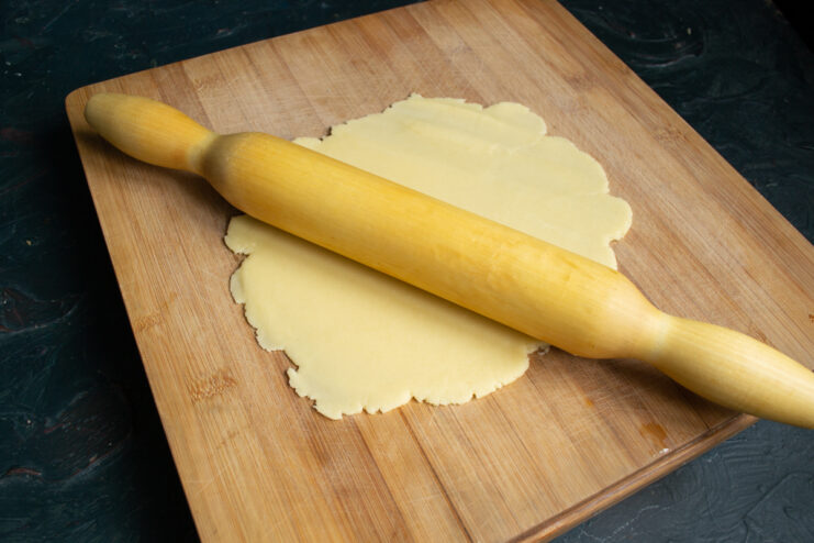 Rolling out the shortcrust pastry Rolling out shortcrust pastry with a wooden rolling pin on a board