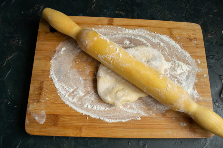 Rolling out the dough Rolling out noodle dough on a wooden board with a rolling pin