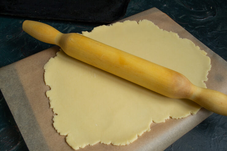 Rolling The Dough Rolling out shortbread dough evenly on parchment paper using a rolling pin