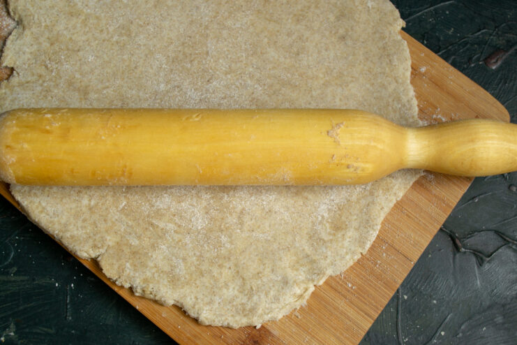 Rolling the Dough Rolling pin flattening dough into a circle on a board