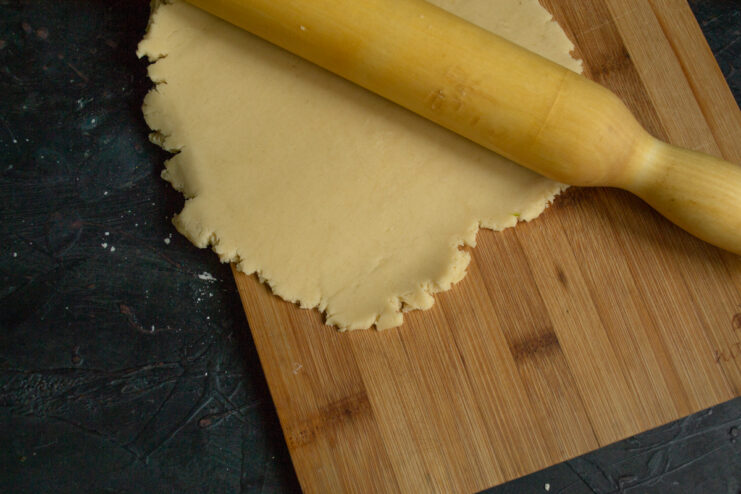 Rolling out the base Rolling out the pie dough on a board with a rolling pin