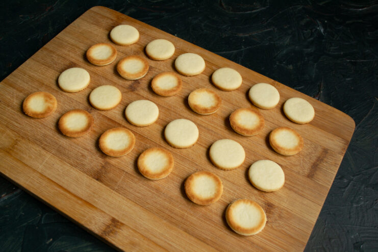 Preparing For Assembly Baked cookie rounds laid out in matching pairs on a wooden board