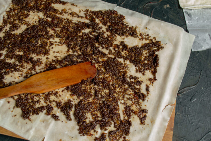 Spreading Filling on Phyllo Spreading poppy seed filling in a thin layer over a sheet of phyllo dough