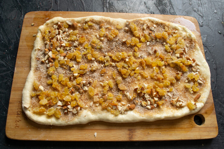 Adding the fruit and nut filling Spreading chopped toasted almonds and soaked raisins over the spiced dough layer