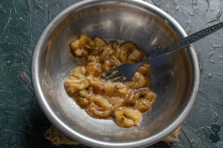 Mashed banana in a metal mixing bowl