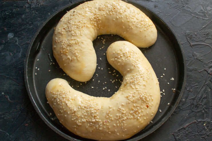 Brushing crescent rolls with egg wash and sprinkling with sesame seeds