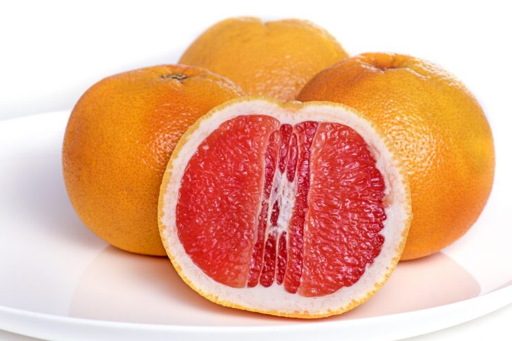 Juicy Pink Grapefruit Halved pink grapefruit revealing vibrant red flesh on a white ceramic plate