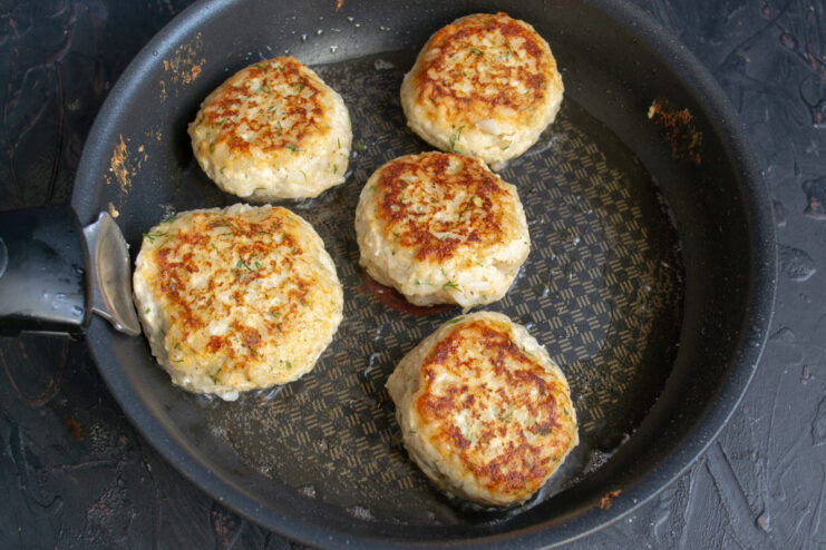 Golden Meatball Crust Browned chicken meatballs flipped in a frying pan.