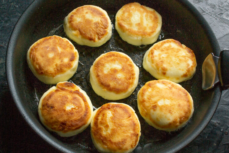 Golden brown syrniki cooking in a frying pan