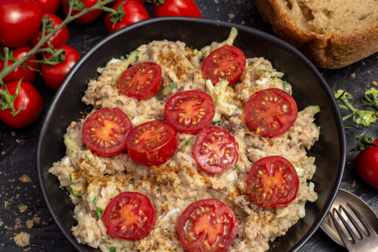 Fish salad with rice and sardines garnished with cherry tomatoes on a plate