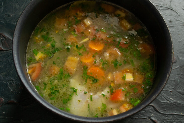 Simmering the broth Fish soup with fresh vegetables and spices simmering gently in a pot