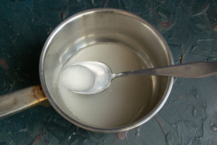 Granulated sugar and water simmering in a saucepan to create a thick syrup