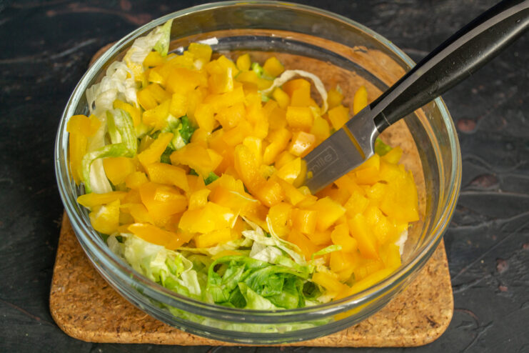 Adding sweet bell pepper Diced yellow sweet bell pepper added to the chopped lettuce