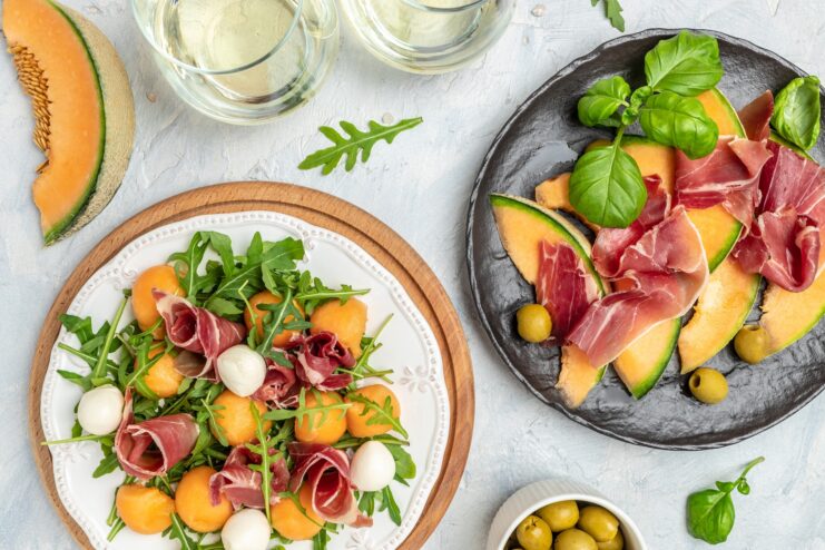 Prosciutto appetizer serving ideas Plate featuring a salad with prosciutto slices, melon balls, fresh mozzarella, and basil