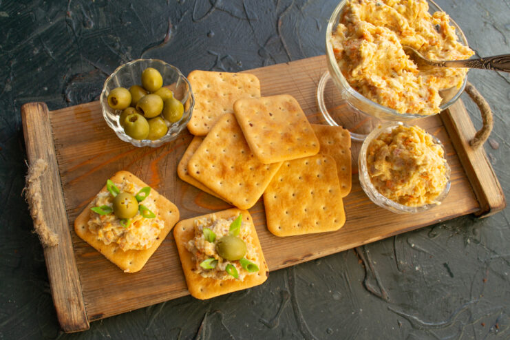 Serving the appetizer Plating vorschmack on crackers with olives on a wooden tray