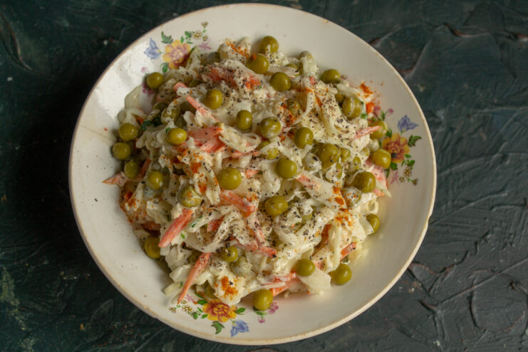 Serving the finished salad Serving of fresh vegan vegetable and pea salad on a patterned plate