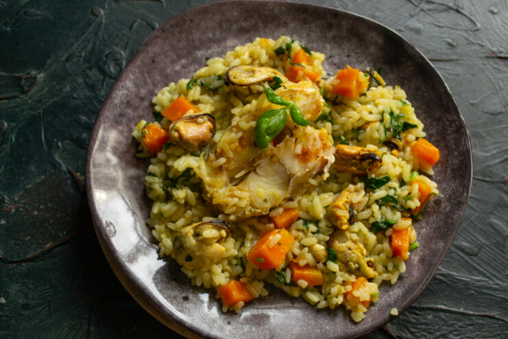 Serving the finished dish Plated fish plov with mussels garnished with fresh basil
