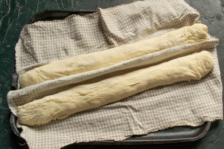 Shaped baguettes resting on a floured baker's couche