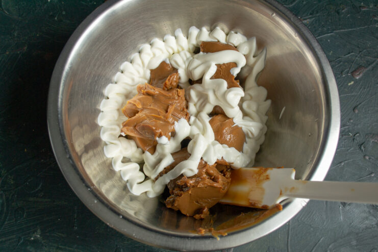 Frosting ingredients Boiled condensed milk and sour cream in a glass mixing bowl