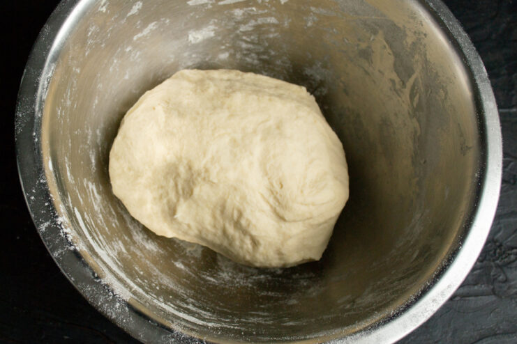 Resting the noodle dough A ball of kneaded noodle dough resting in a metal bowl