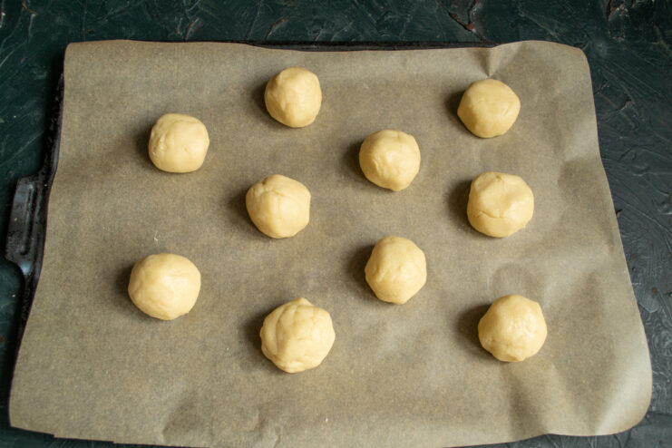 Shaping The Cookies Dough balls on a parchment lined baking sheet