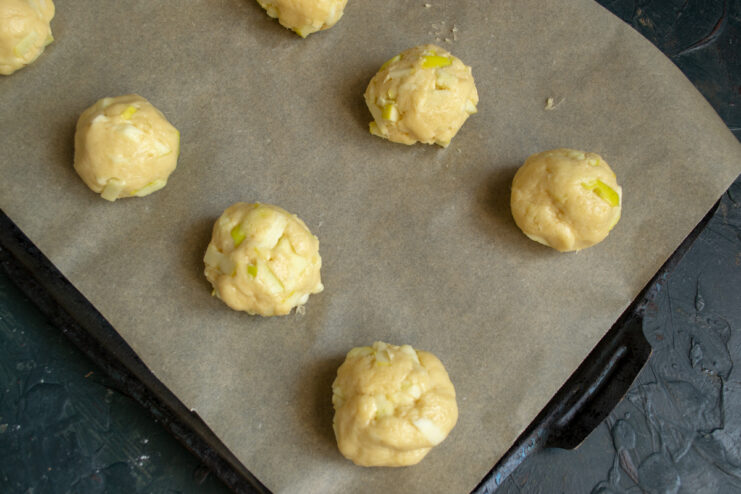 Raw cookie dough balls arranged on a parchment-lined baking sheet
