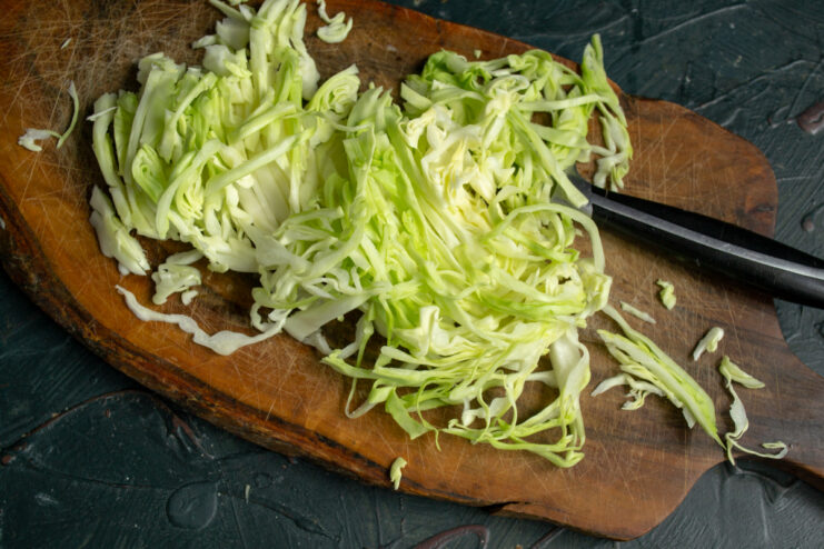 Shredding cabbage for the salad Thinly shredded Napa cabbage on a wooden cutting board