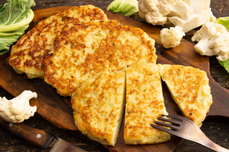 Crispy golden cauliflower schnitzel resting on a wooden cutting board