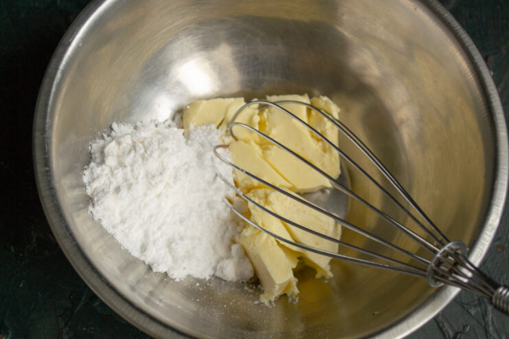 Creaming the Butter Softened butter mixed with powdered sugar in a bowl with a whisk