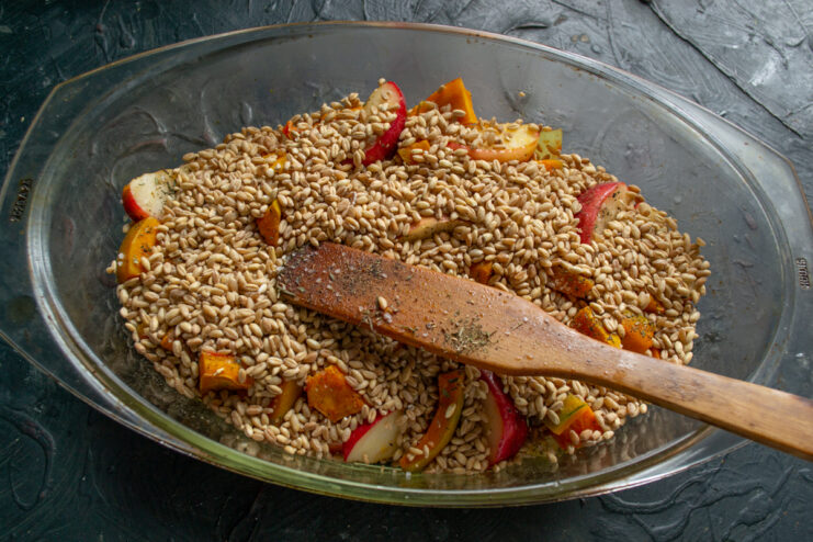 Adding the farro Layer of dry farro over vegetables and meat in a baking dish