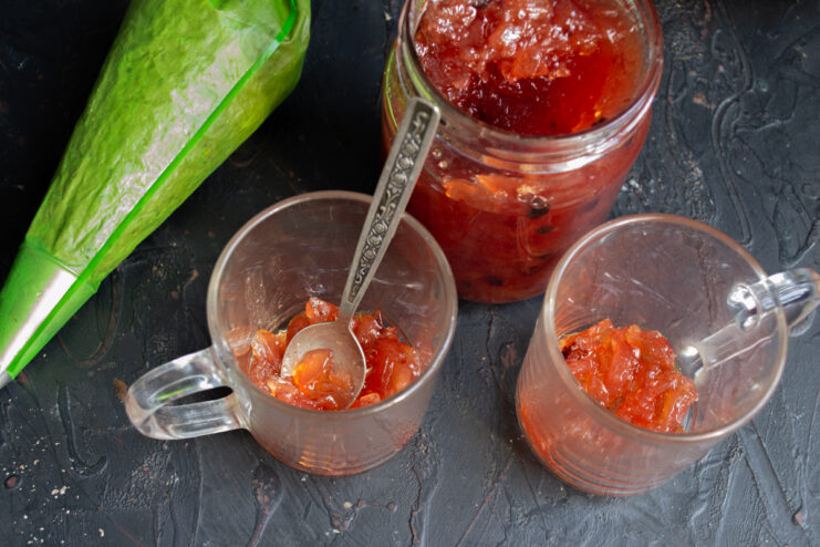 A layer of apple-cranberry jam at the bottom of a clear mug.