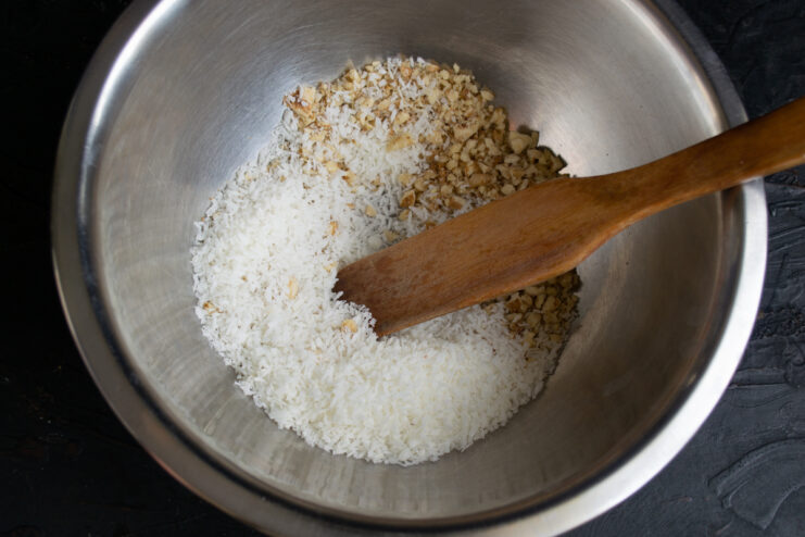Mixing nuts and coconut Crushed walnuts mixed with shredded coconut in a stainless steel bowl