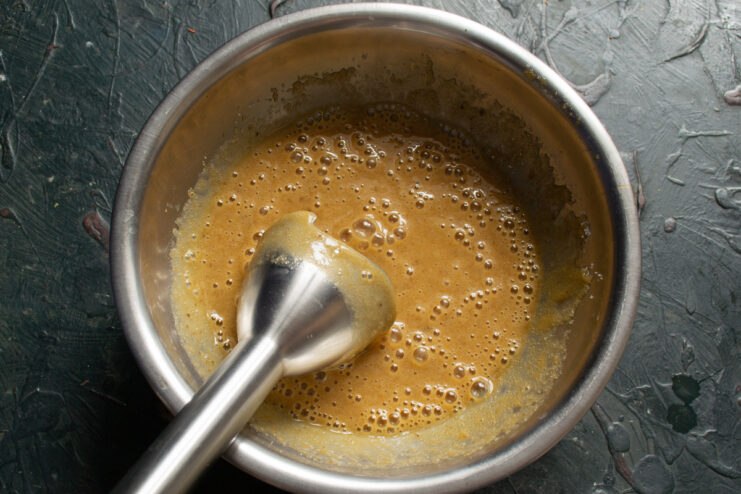 Blending wet ingredients in a bowl with an immersion blender