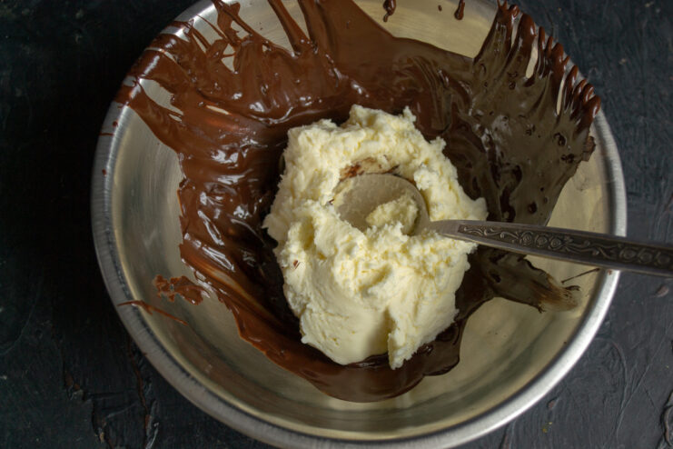 Mixing mascarpone with melted dark chocolate in a bowl.