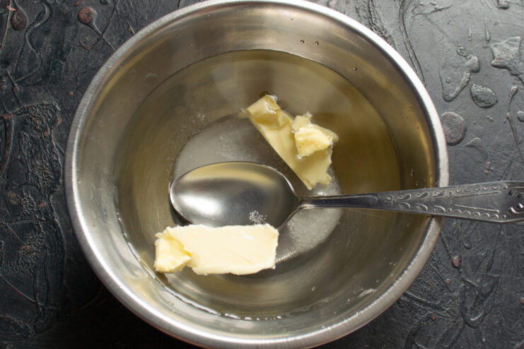 Mixing the wet ingredients Whisking melted butter, granulated sugar, and warm water in a bowl